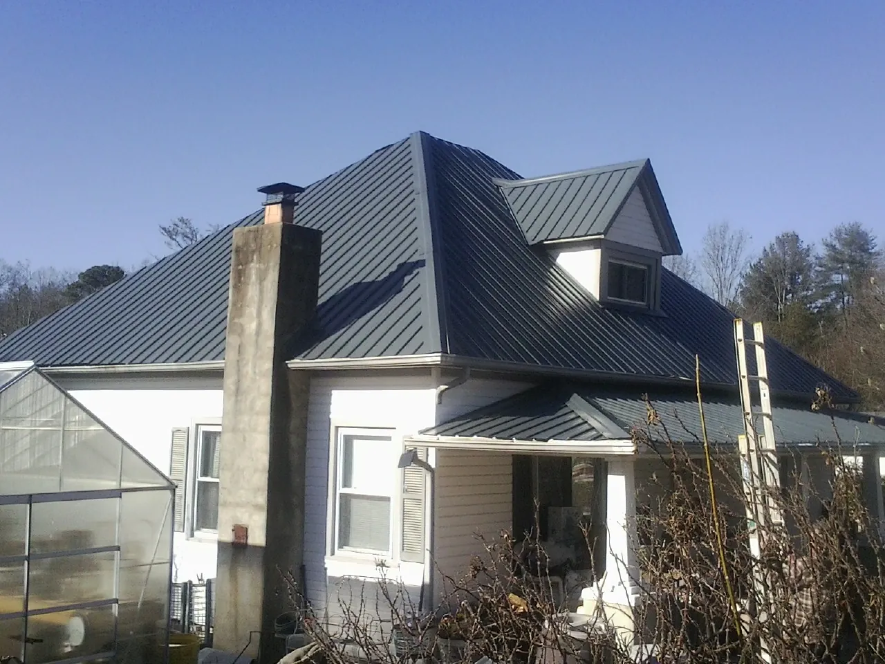 Dark blue standing seam metal roof on a white farmhouse with dormer — Slate & Tile Roof Repair by Roofing Brothers in Plant City