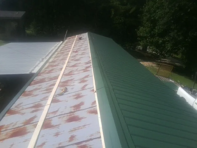 Old rusted panels beside newly installed green metal roofing — Wind Damage Roof Repair by Roofing Brothers in Plant City