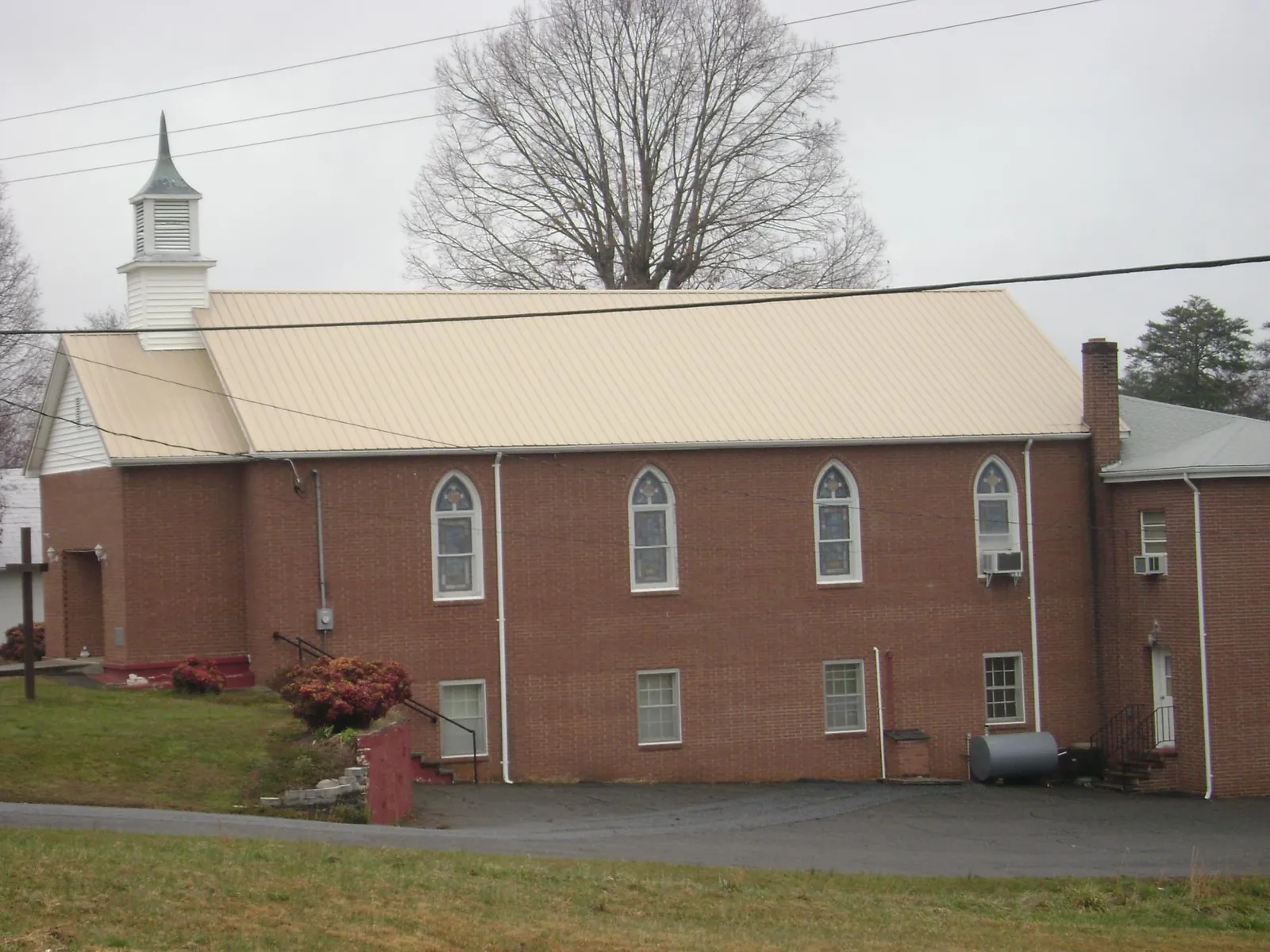 New tan metal roof on a brick church with a white steeple in Plant City