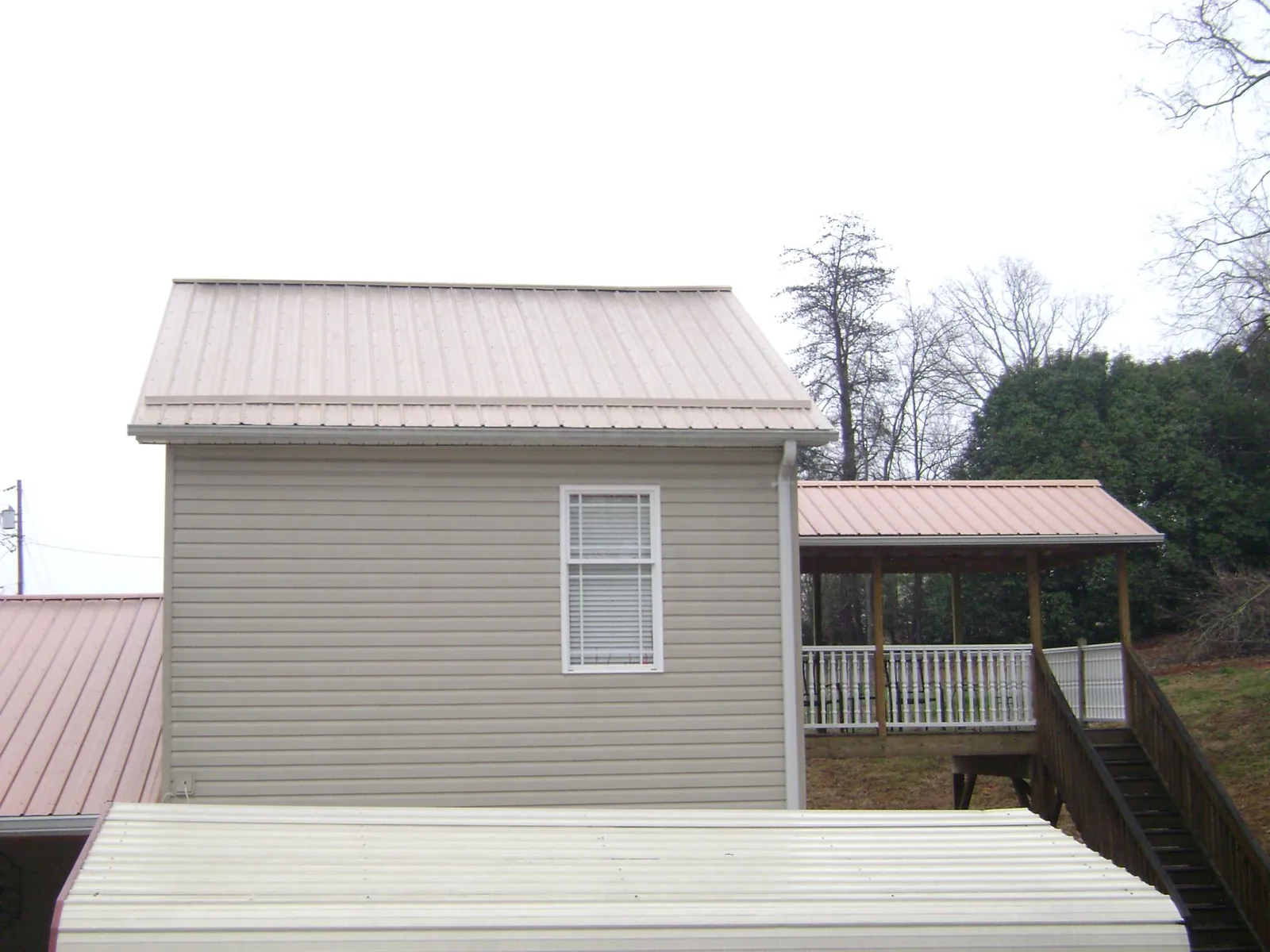 Tan metal roofs on a two story addition and attached porch, from a Roof Replacement job in Plant City
