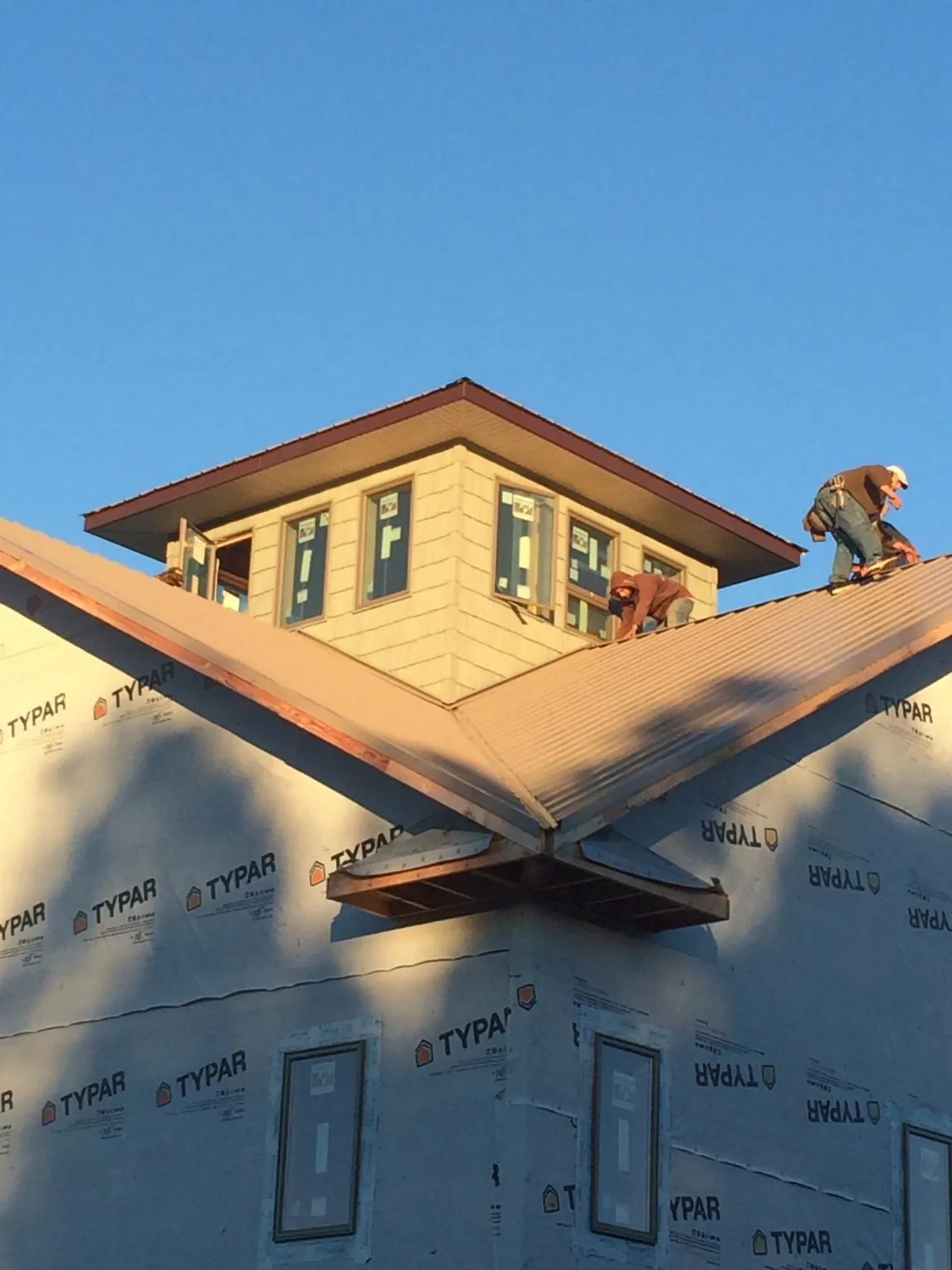 Roofers working around a rooftop cupola on a new metal roof at sunset — Roof Waterproofing in Plant City by Roofing Brothers